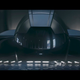 A driver in a race car looks through their helmet at the camera.